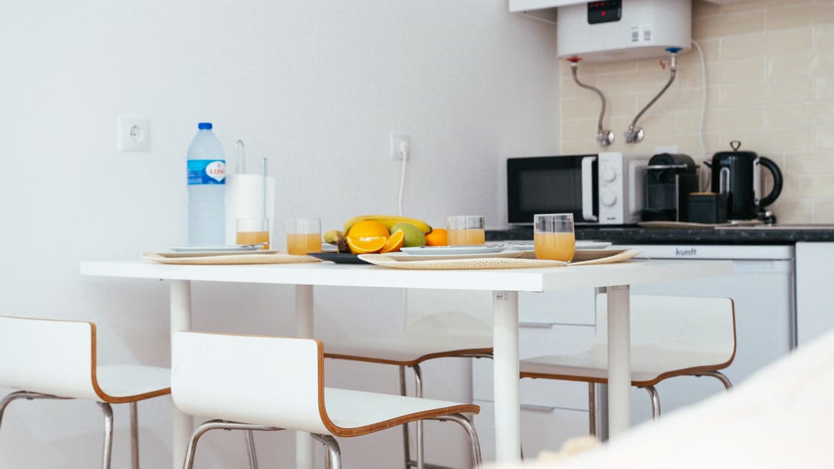 A modern kitchen with a neatly arranged table setting featuring fruit and juice, capturing a minimalist interior design.